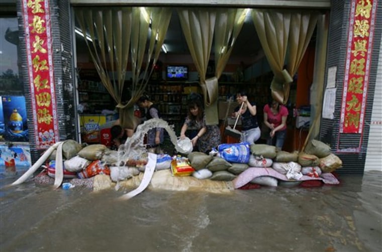 A woman uses a pail to remove water from a flooded store in Wuhan, China, on Saturday.